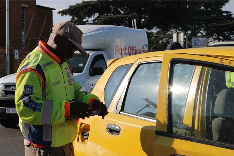 Uniformed officer standing at a yellow car