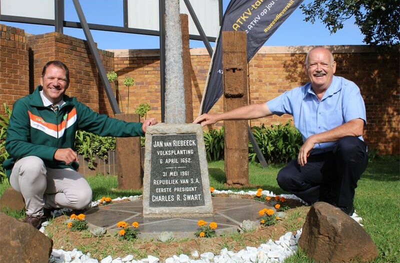 Twee wit mans kniel by 'n monument