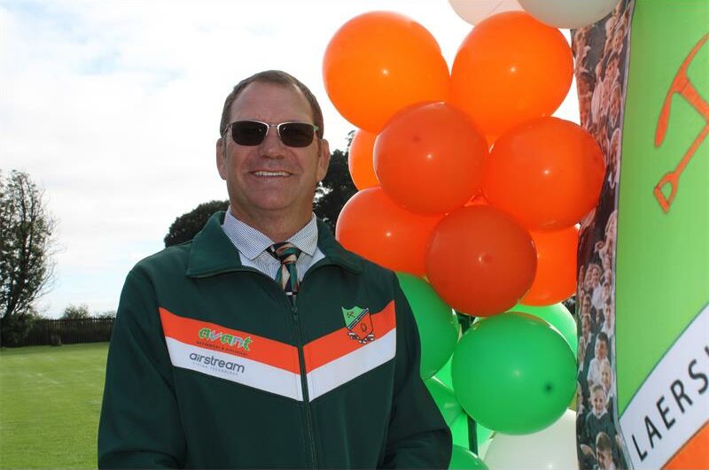 Man met donkerbrille wat langs oranja en groen ballonne staan