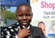 Black boy smiles while holding a black and white paw-print blanket