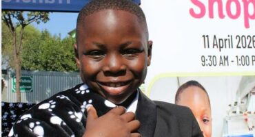 Black boy smiles while holding a black and white paw-print blanket
