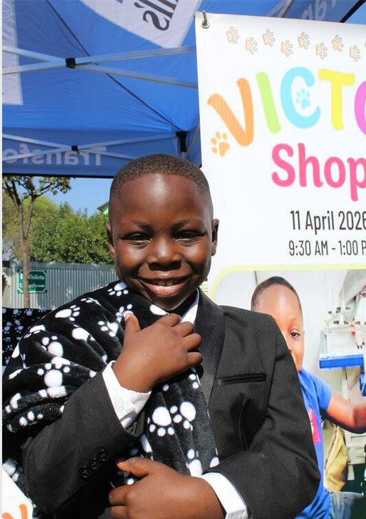 Black boy smiles while holding a black and white paw-print blanket