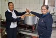 Two women, one black and one white stirring a pot of soup