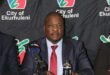 Executive Mayor Nkosindiphile Xhakaza sitting at a desk with the Ekurhuleni Metro back drop
