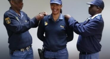 Two male police officers flanking a female officer