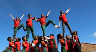 Group of black girls in uniform making an aerial cheerleading formation