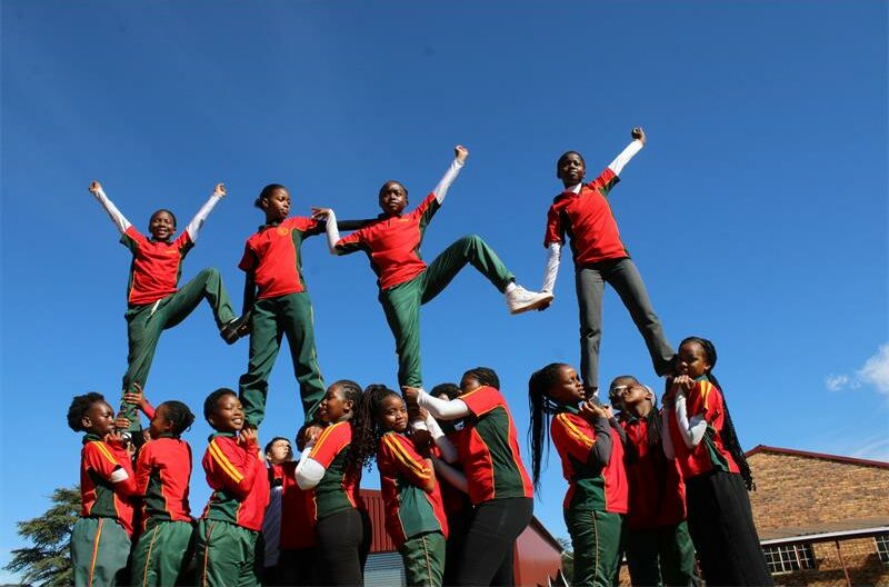Group of black girls in uniform making an aerial cheerleading formation