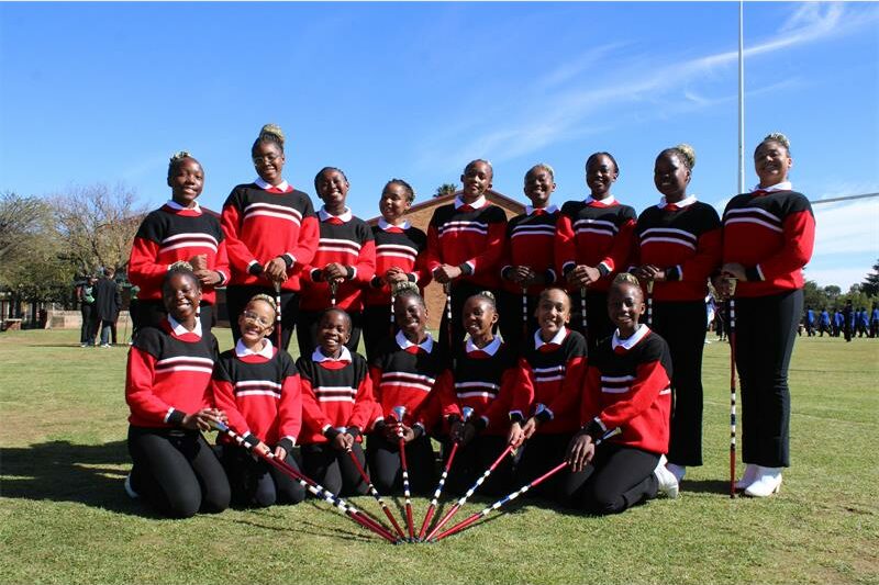 Group of girls in an oval formation holding maces