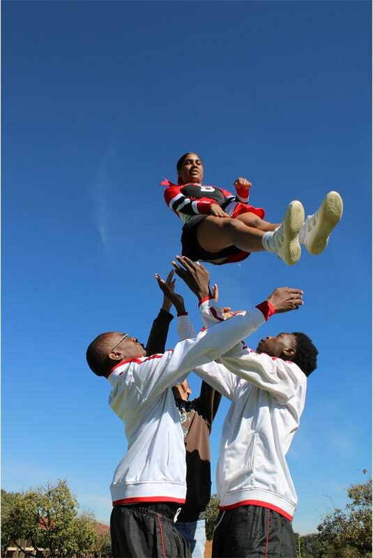 Cheerleader is airbourne with two boys ready to catch her