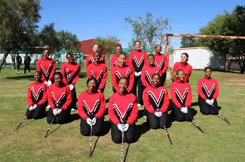 Group of girls in matching uniforms holding maces