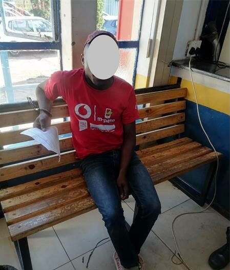 Man wearing a red shit shits on a bench. His face is blocked out