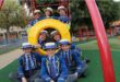 Group of school children wearing straw hats pose a playground equipment