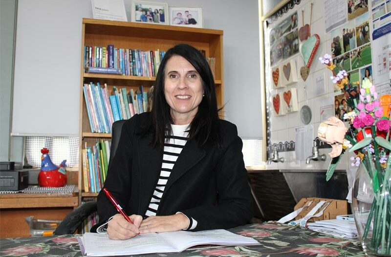 White woman with black hair marking a book at a desk