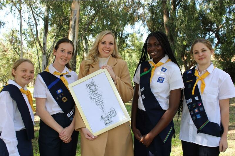 Girl Guides is uniform stand next to a blonde woman holding a picture frame