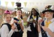Four girls wearing hats and holding tea cups