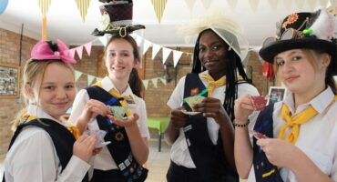 Four girls wearing hats and holding tea cups