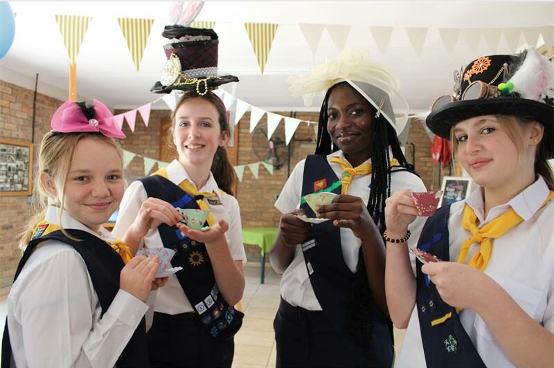 Four girls wearing hats and holding tea cups