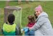 Woman and two children painting a concrete dustbin