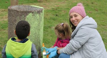 Woman and two children painting a concrete dustbin