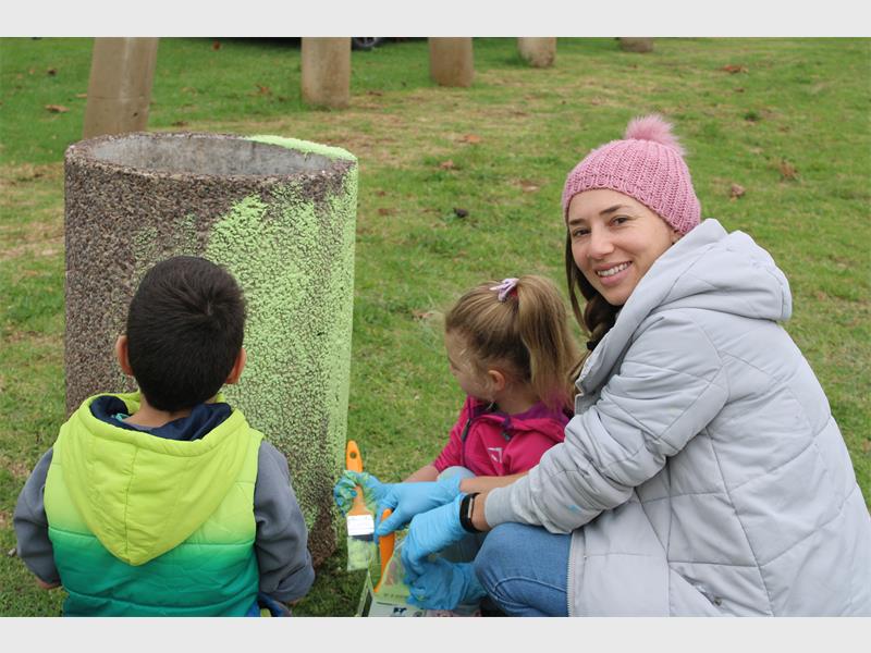 Woman and two children painting a concrete dustbin