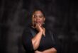 Black woman standing in front of a black background