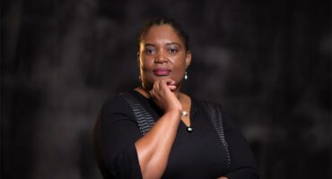 Black woman standing in front of a black background