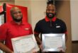 Two black men holding certificates