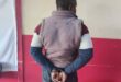 Black man in handcuffs facing the wall
