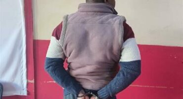 Black man in handcuffs facing the wall