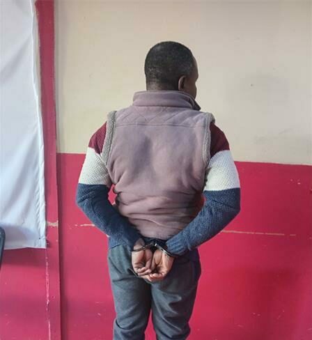 Black man in handcuffs facing the wall