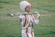 A girl in white and red majorette uniform holding a stick