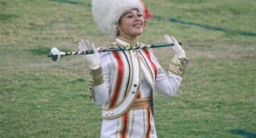 A girl in white and red majorette uniform holding a stick