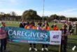 Community group holding "Caregivers Facing Cancer Together" banner at outdoor event in Benoni.