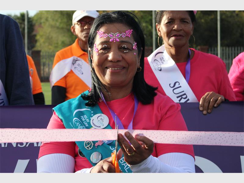 An Indian woman smiling as she cuts a ribbon to mark the opening of a Cansa Relay for Life.