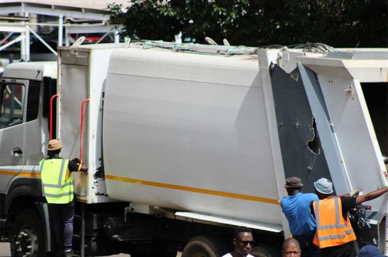 File image of a waste removal truck with men hanging on the sides