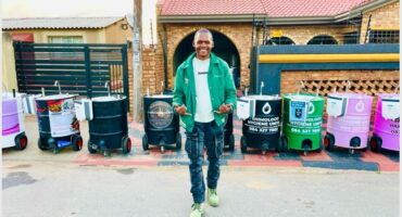 A guy standing in front of colourful hand washing stations.