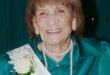 Elderly woman wearing a tiara and a sash with the number 100 in gold