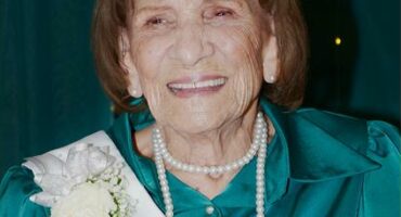 Elderly woman wearing a tiara and a sash with the number 100 in gold