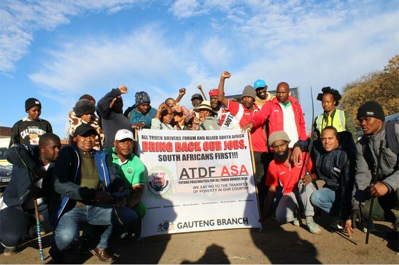 Group of people, some with their hands in fists pose with a banner