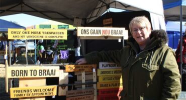 Woman smiling while standing next to a display of wooden sign boards