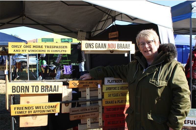 Woman smiling while standing next to a display of wooden sign boards