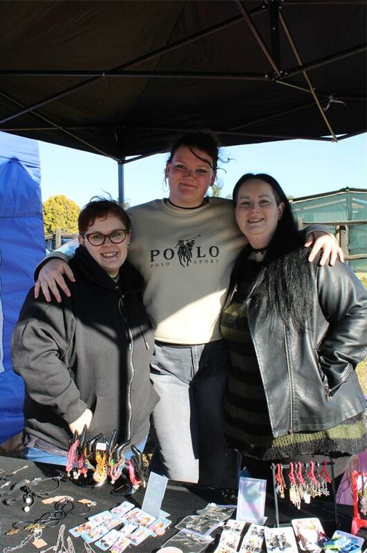 Three women standing behind a display table