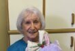 Elderly woman holding a purple stuffed toy