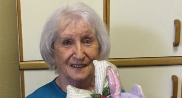 Elderly woman holding a purple stuffed toy
