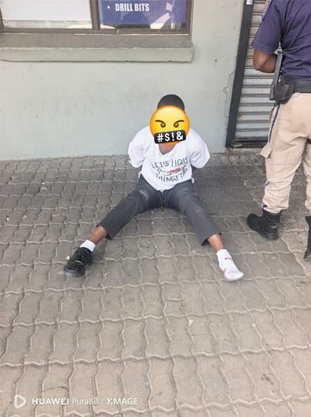 Man sitting on the pavement with an emoji masking his identity.