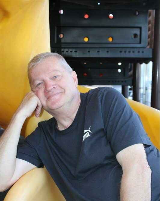 Elderly man sitting comfortably on a yellow slide