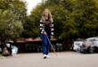 Woman with blonde hair walks through a parking area holding a white cane