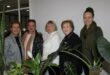 Group of women standing behind plants