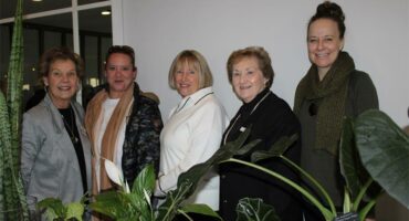 Group of women standing behind plants