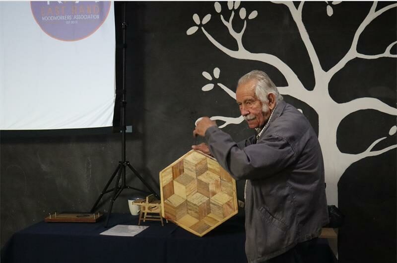 Elderly man standing with a hand crafted wooden table